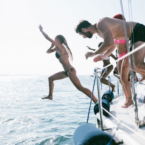 Fiends having fun on a sail boat and jump in the water