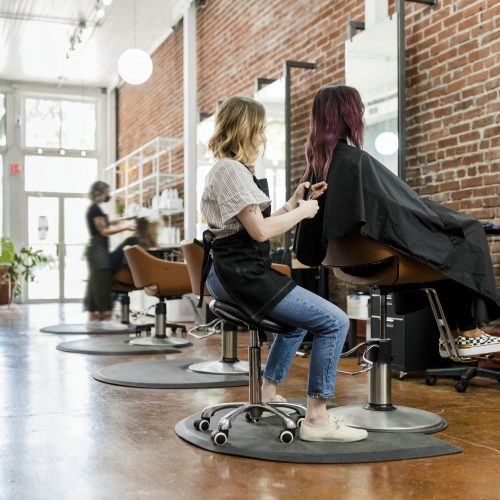 Hairstylist trimming hair of the customer in a beauty salon