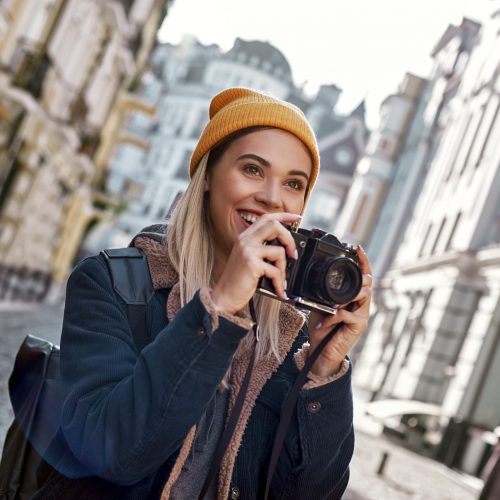 Woman tourist with a camera in historical old city. Free casual style